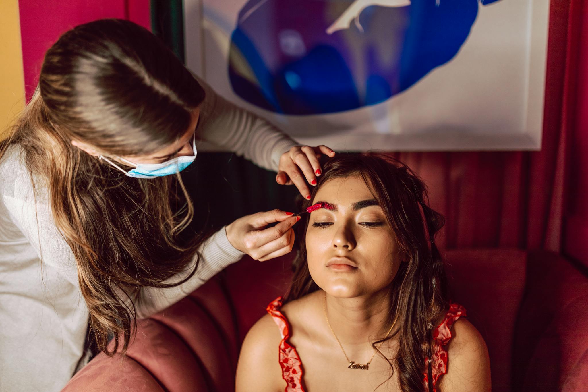 A makeup artist applies makeup to a woman indoors, showcasing beauty and skill.